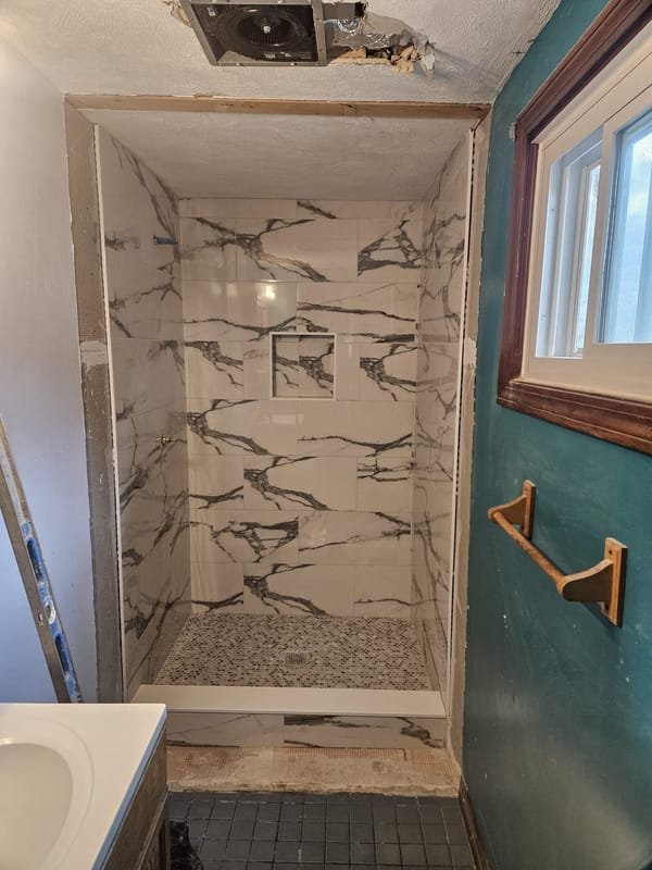 Marble-look shower surround with a pebble floor