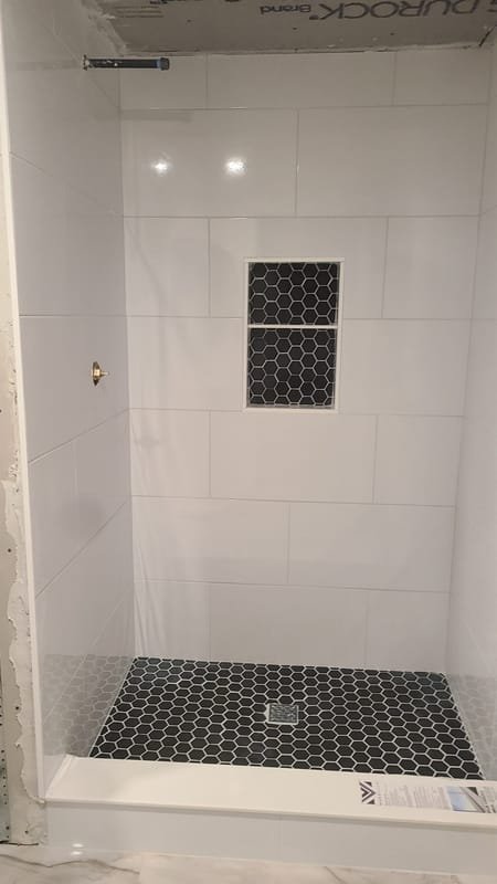 White tile shower with a black hexagon niche and floor