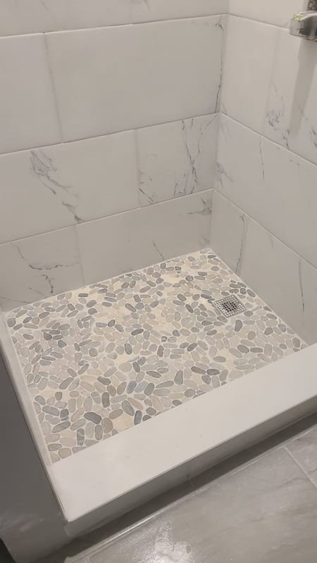 Marble-look shower with a natural pebble-stone pan
