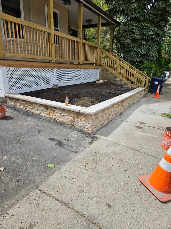 Tan stacked-stone veneer garden wall with granite cap