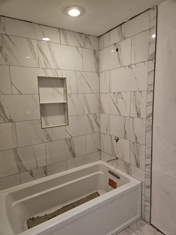 White marble-look tile tub surround with a niche